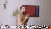 a man with a beard is clapping in front of a painting that says e um filhote de cachorro