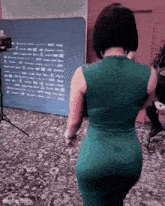 a woman in a green dress is standing in front of a projector screen .