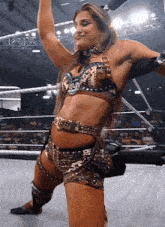 a woman in a wrestling ring with her arms up in the air