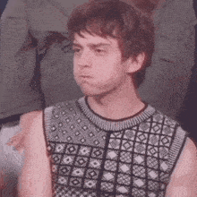 a man wearing a black and white sweater is making a funny face .