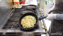 a person is cooking food in a frying pan on a stove with a bottle of sauce in the background