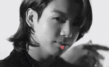 a black and white photo of a man with a heart in his mouth and a piercing on his forehead .