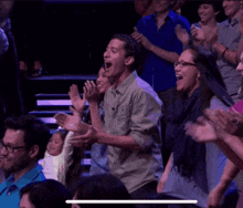 a group of people are sitting in a theatre with their arms in the air