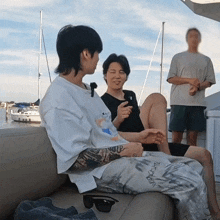 two men are sitting on a couch and one has a tattoo on his arm that says ' i love you '