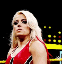 a woman in a red and black top is standing in a wrestling ring