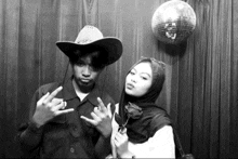a man wearing a cowboy hat and a woman wearing a hijab pose for a photo