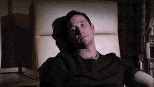 a man in a black shirt is laying in a hospital chair