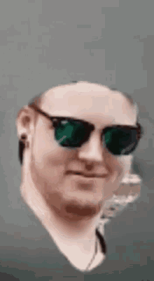 a man wearing sunglasses and a beard is smiling .