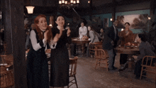 a group of people are clapping and smiling in a restaurant
