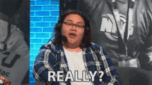 a man wearing headphones says " really " in front of a brick wall