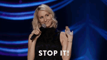 a woman is holding a microphone on a stage and says `` stop it '' .
