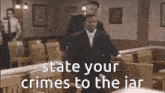 a man in a suit is walking in a courtroom with the words `` state your crimes to the jar ''