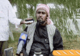 a man wearing a head scarf is being interviewed by someone