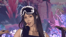 a woman wearing ski goggles on a stage with a kbs logo in the background