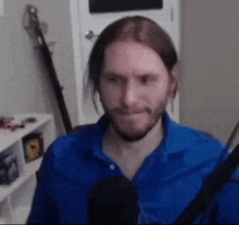a man with long hair and a beard is sitting in front of a microphone and making a funny face .