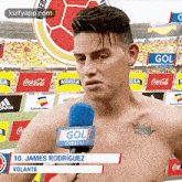 a shirtless soccer player is talking into a microphone in front of a crowd .