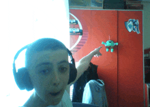 a boy wearing headphones points to a stuffed animal on the wall