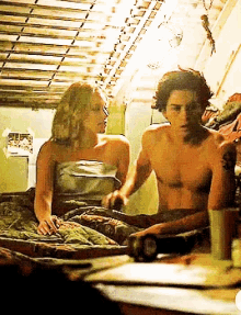 a man and a woman are laying on a bed and the woman is wrapped in a blanket