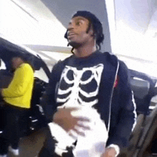 a man wearing a skeleton sweater is holding a piece of paper in a parking garage .