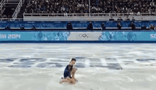 a female figure skater is kneeling on the ice in front of a sign that says 2014