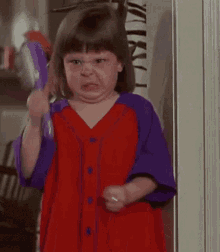 a little girl is making a funny face while brushing her hair .