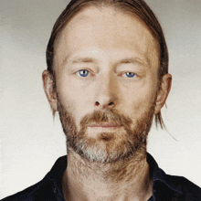 a man with a beard and blue eyes is wearing a black shirt