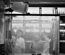 a black and white photo of a man pouring water into a tank with a statue of liberty in the background