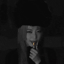 a woman in a black hat is lighting a cigarette with a lighter