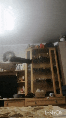 a person is holding a gun in a living room with a clock on the wall behind them