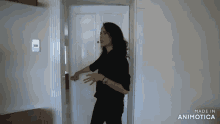 a woman in a black shirt is standing in a doorway .
