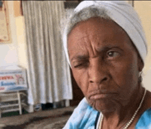 an elderly woman is making a funny face while wearing a white headband and pearls .