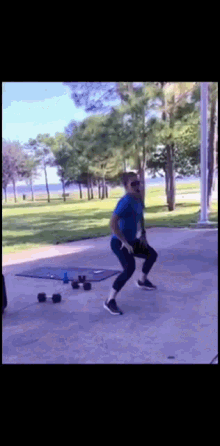 a man in a blue shirt is doing squats on a concrete surface