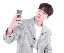 a man in a grey jacket is taking a selfie with his cell phone