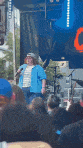a man singing into a microphone in front of a crowd with a sign that says c on it