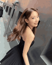 a woman in a black dress stands in front of a building