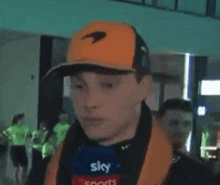 a man wearing an orange hat and a blue microphone with the word sky on it .