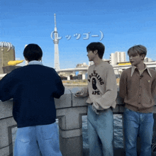 a man wearing a bathing ape sweater stands on a bridge