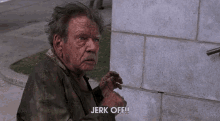 an elderly man is standing next to a brick wall and says jerk off .