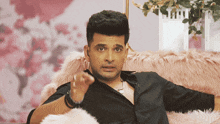 a man in a black shirt is sitting on a pink fur couch