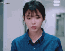 a woman wearing a blue shirt is looking down