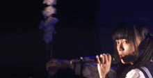 a girl in a school uniform singing into a microphone in a dark room ..
