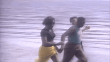 a group of people are dancing in the water on a beach holding hands .