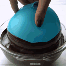 a person is dipping a blue balloon in chocolate