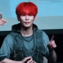 a man with red hair is wearing a gray shirt and a black vest