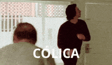 a man is standing in front of a door with the word colica written on it