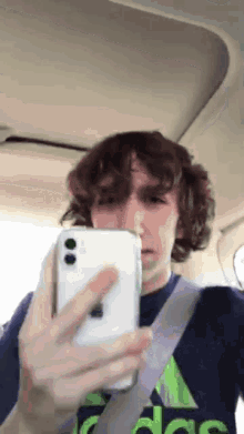 a man in an adidas shirt is taking a picture of himself with his phone