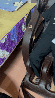 a person is sitting in a chair with a purple blanket on the bed