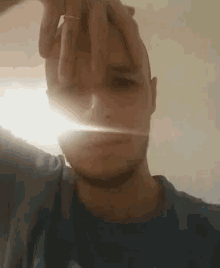 a man in a blue shirt is making a funny face with his hands .