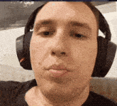 a close up of a man wearing headphones and making a silly face
