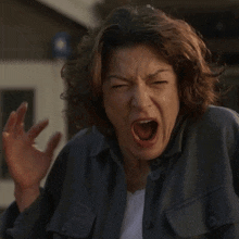 a woman in a blue jacket is making a funny face with her mouth open